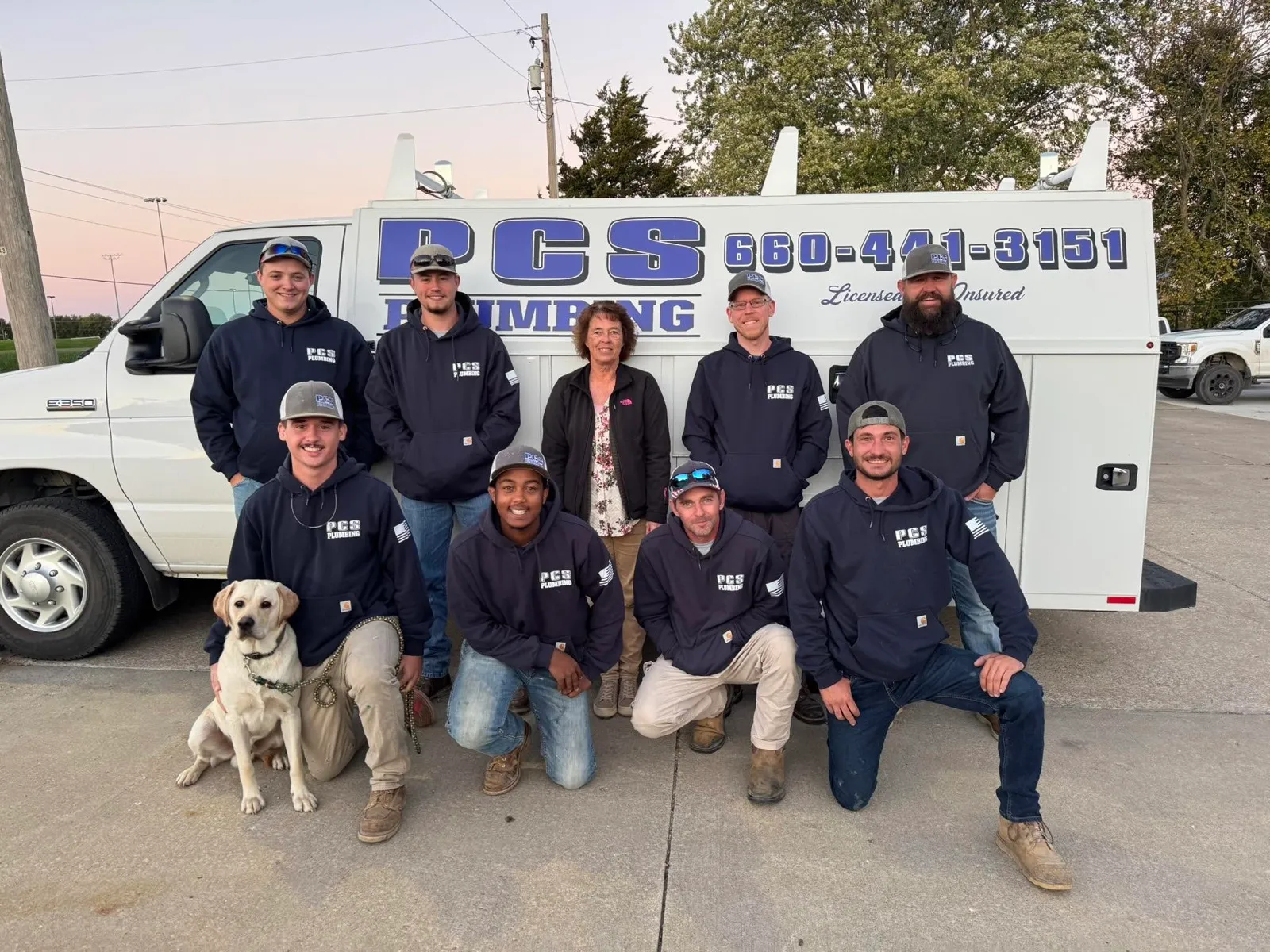 The PCS Plumbing crew in front of a company truck at dusk